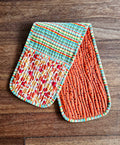 Two colorful quilted pot holders on a wooden surface