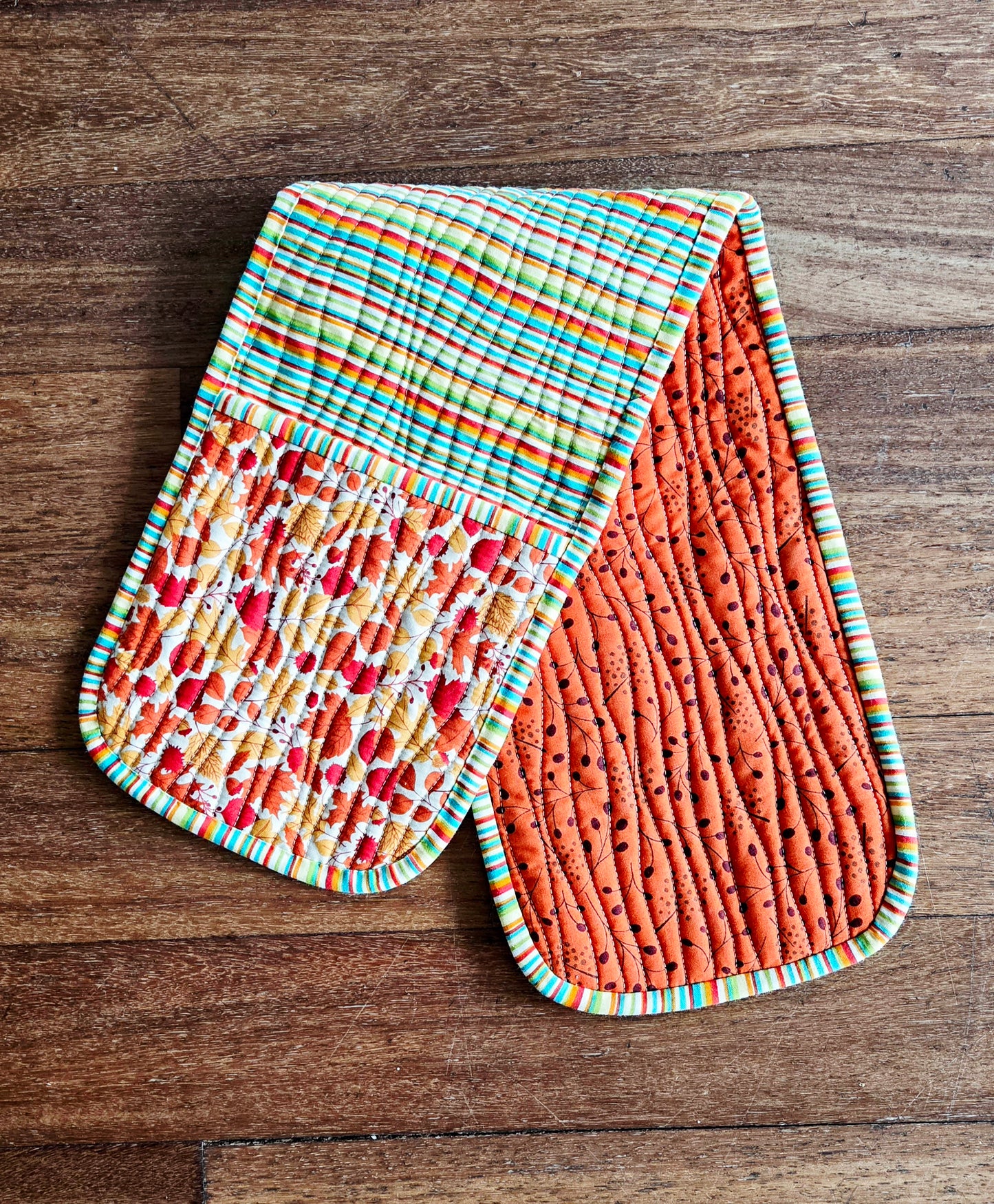 Two colorful quilted pot holders on a wooden surface