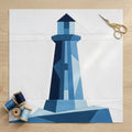 Geometric lighthouse craft project on white paper with scissors and thread spools on a wooden surface.