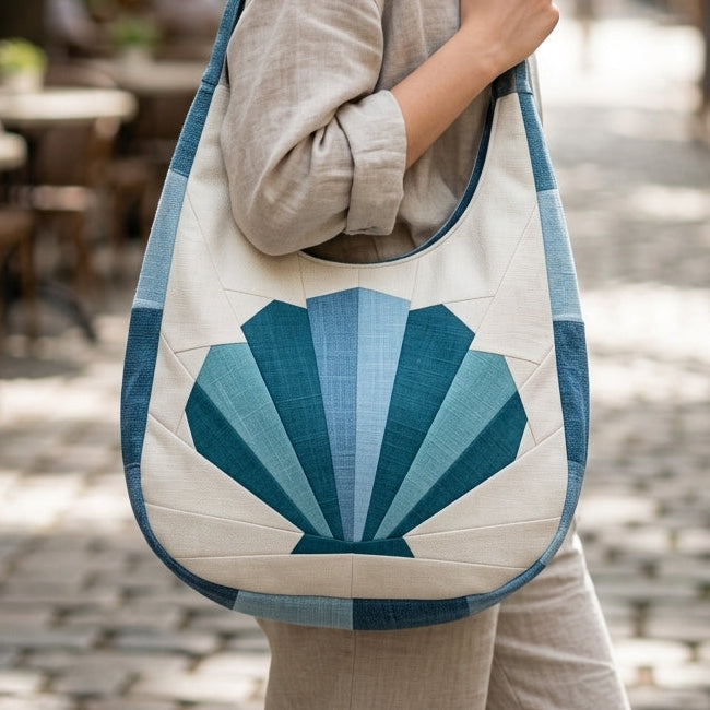 Woman holding a blue and white tote bag with a shell design in an outdoor setting.